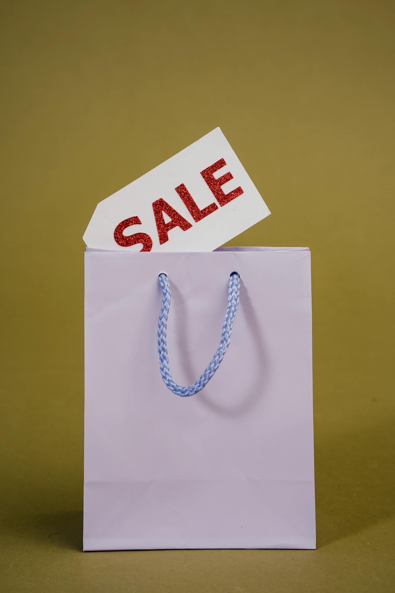 A purple shopping bag with a vibrant sale tag on a green background, perfect for retail promotions.