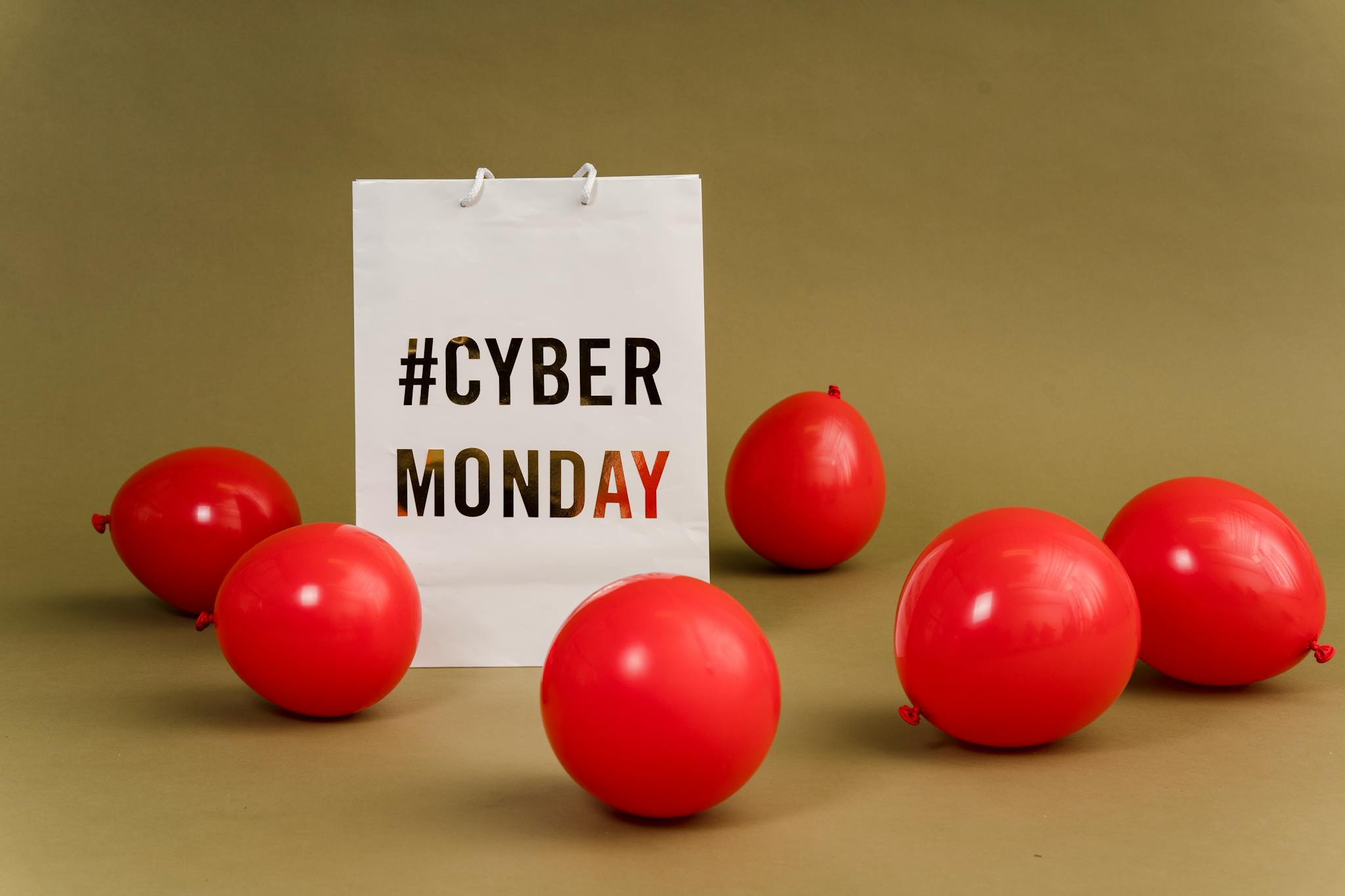 Shopping bag with hashtag Cyber Monday surrounded by vibrant red balloons.